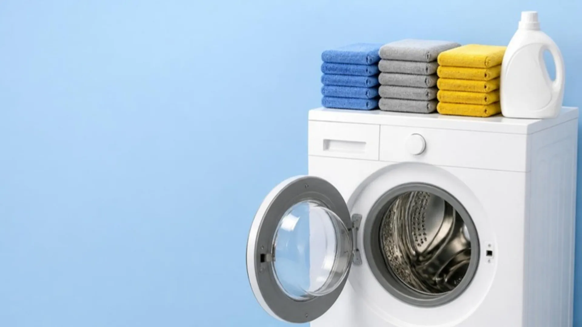 Illustration of a washing machine with its door open and three stacks of folded microfiber towels, blue, gray and yellow, on top beside a detergent jug